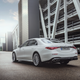 a white 2023 mercedes-amg s 63 e performance sedan seen from the rear, parked in a generic industrial complex surrounded by parking garages